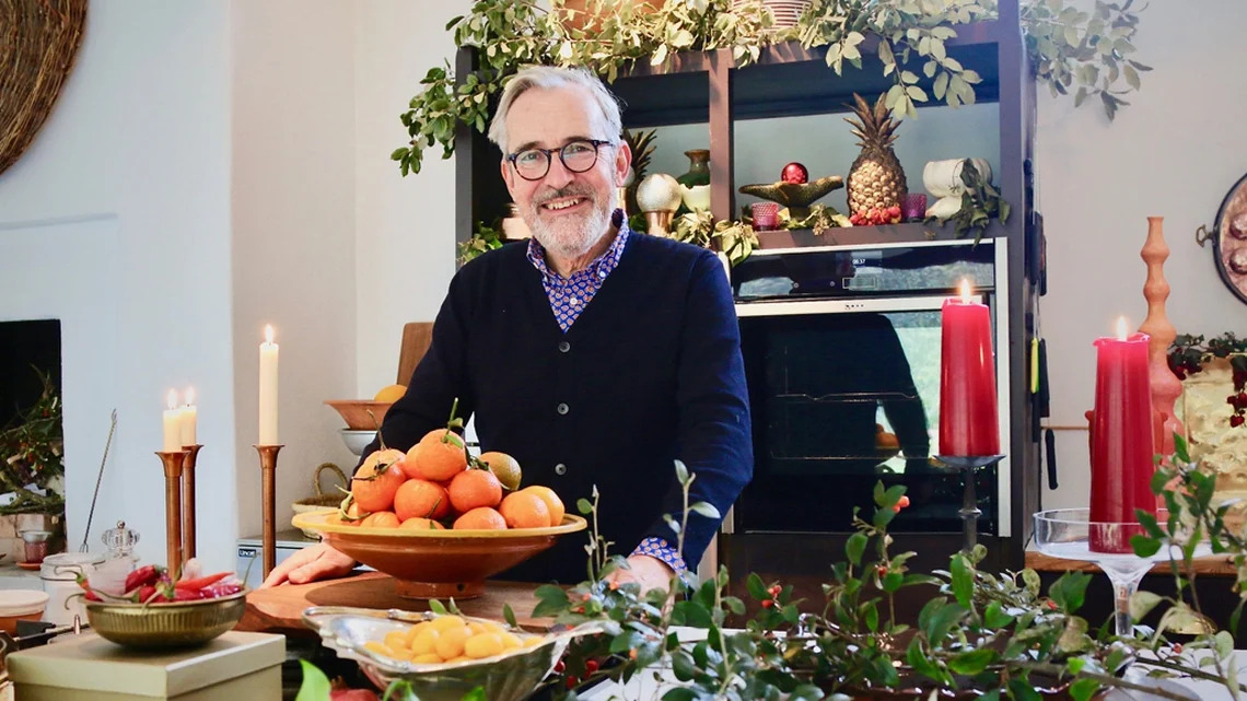 TV Chef Rory O'Connell stands with ingredients in a room decorated for Christmas